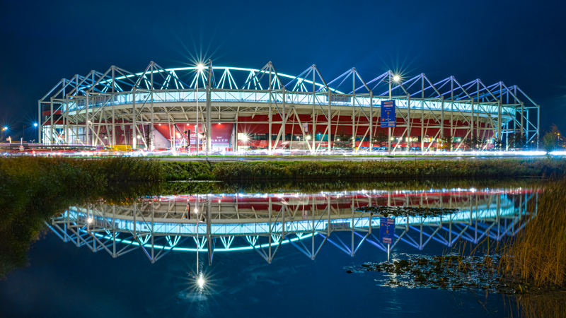 Foto van AZ stadion in de avond met reflectie in het water